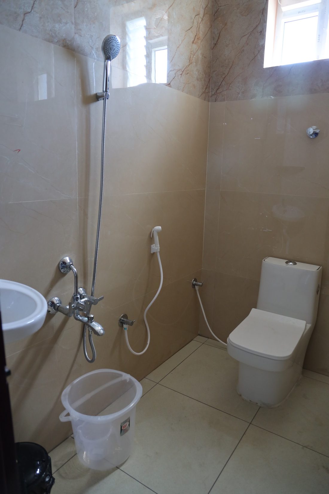 A second bathroom with a corner washbasin, wall mixer and shower.