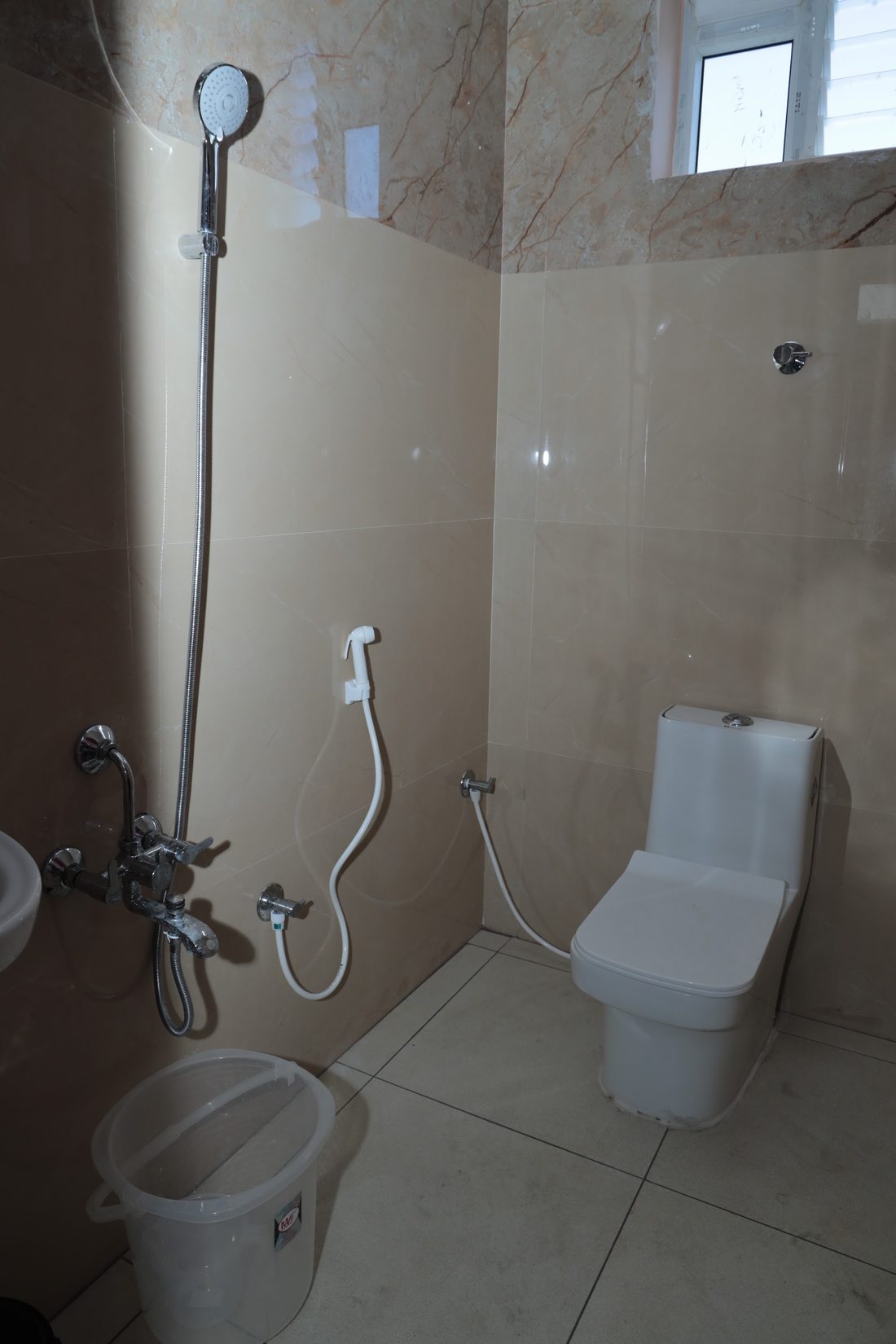 A bathroom with an overhead shower, a wall mixer, a western WC and a washbasin.