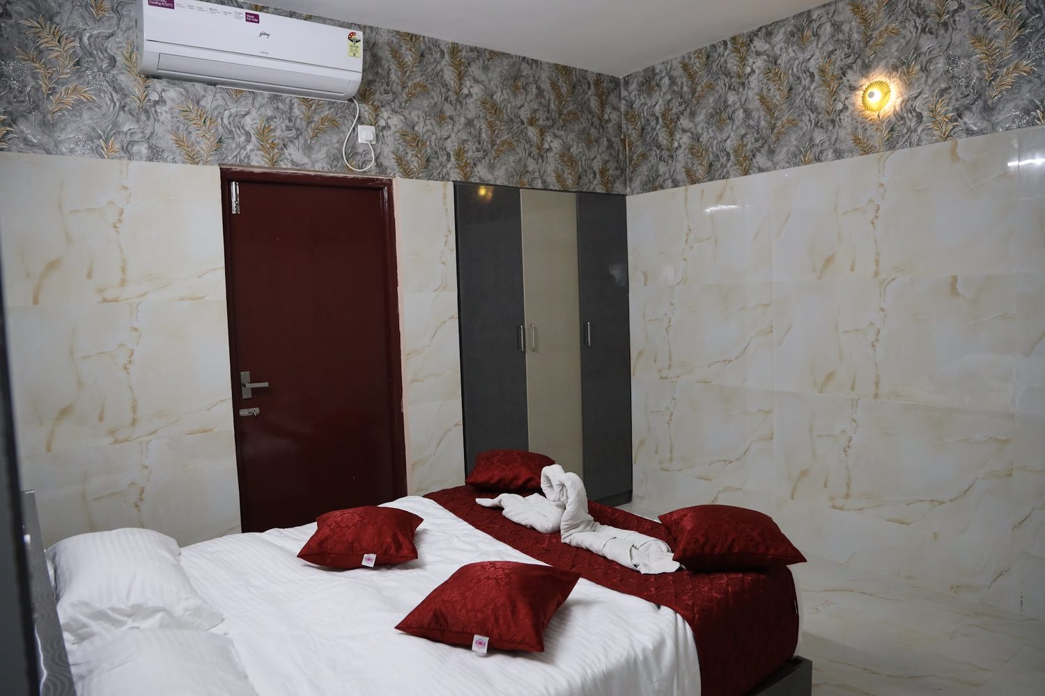 A family unit with two beds made up side by side under a patterned cornice, with an air-conditioner and wardrobes along the wall.